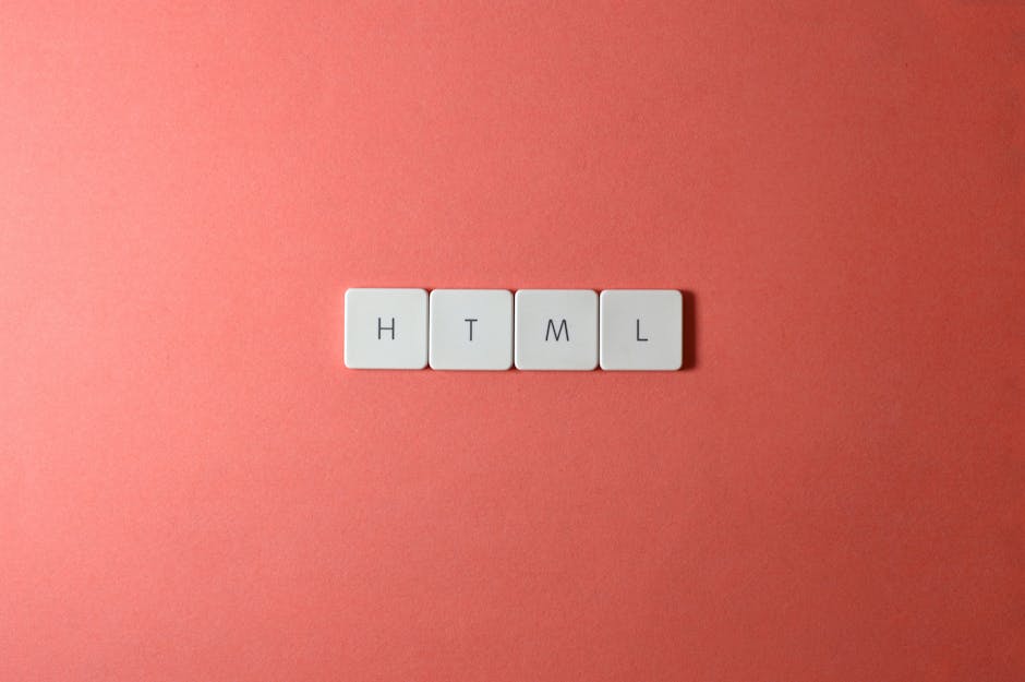 A close-up image showing four small white rectangular tiles arranged in a straight line on a flat pink surface. Each tile has a black letter, spelling out 'HTML'. The tiles are evenly spaced, and the 