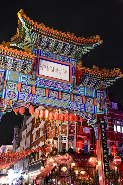 A traditional Chinese building with ornate architectural details and a multi-tiered, curved roof decorated with colorful patterns and lights, illuminated against a night sky. The building features Chi